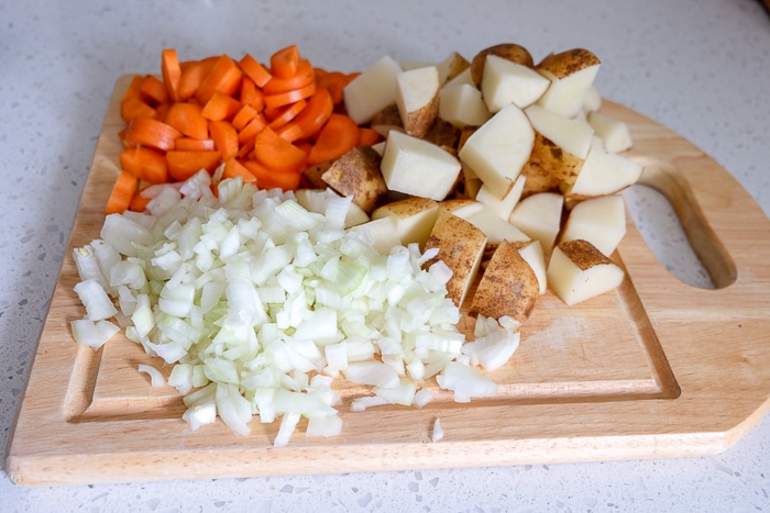 chopped onion potato and carrots on wooden board