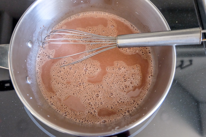 chocolate panna cotta ingredients boiling in silver pot on stove top