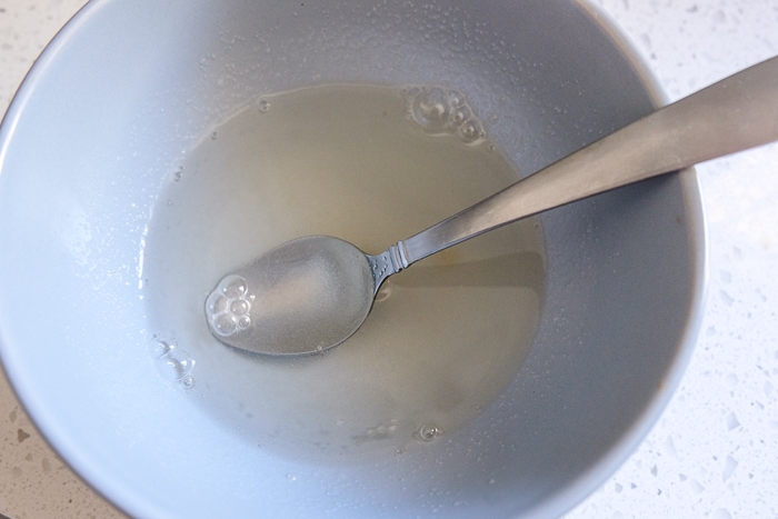 gelatin being stirred with silver spoon in grey bowl