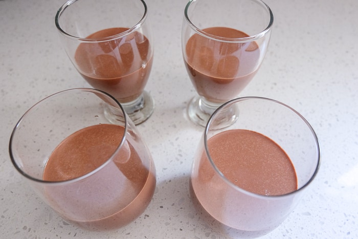chocolate panna cotta in serving glasses on white counter top