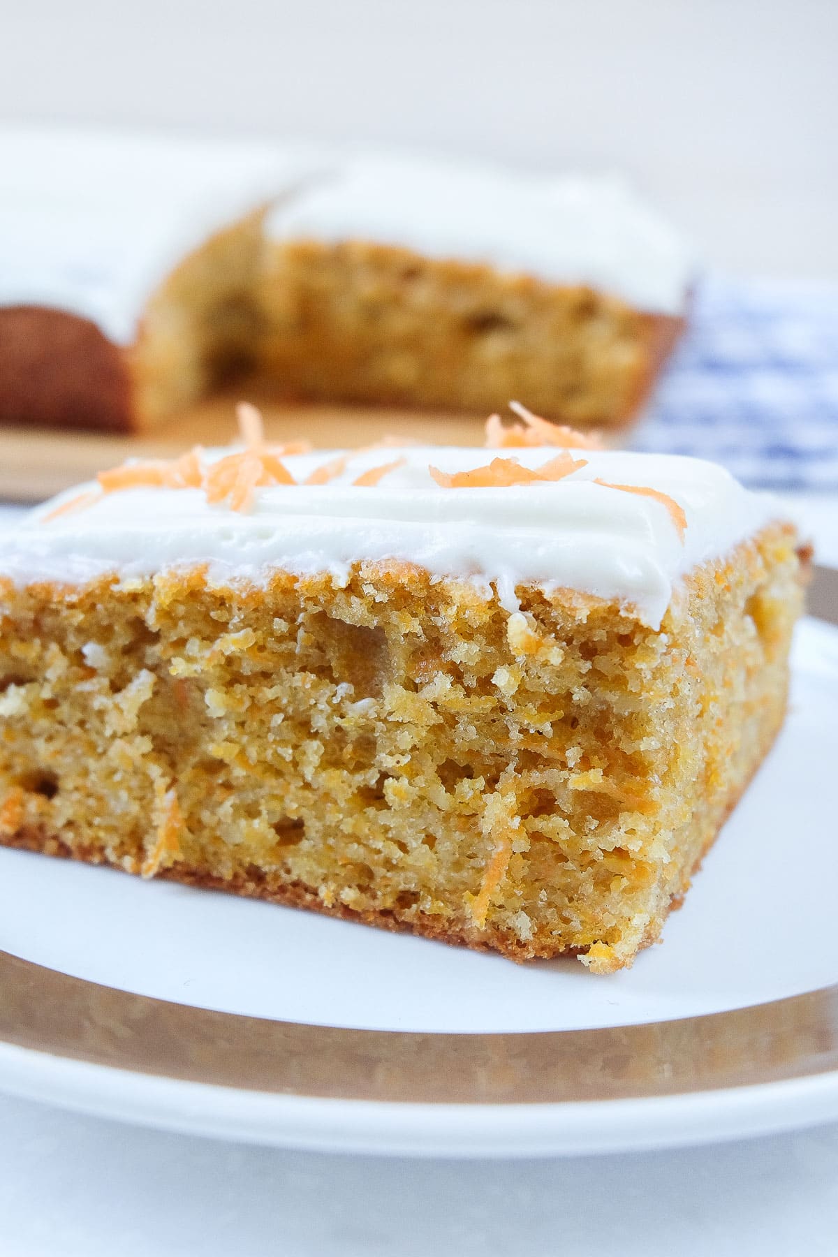 slice of carrot cake on plate with full cake behind