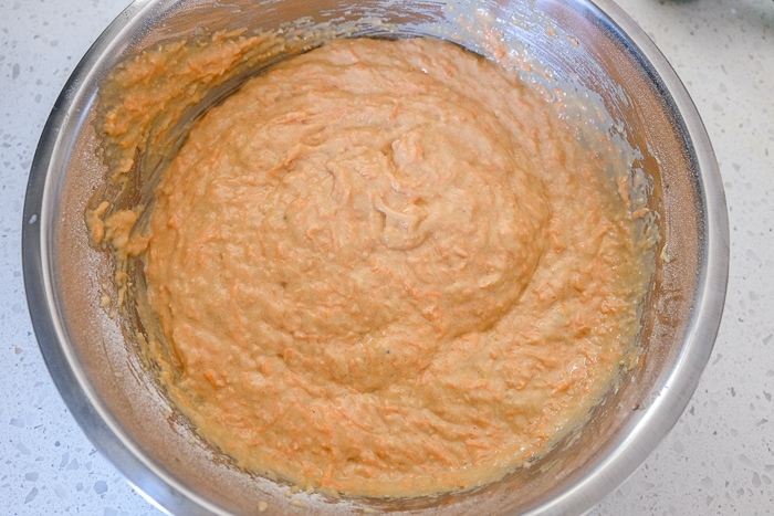 orange carrot cake batter in silver mixing bowl on counter