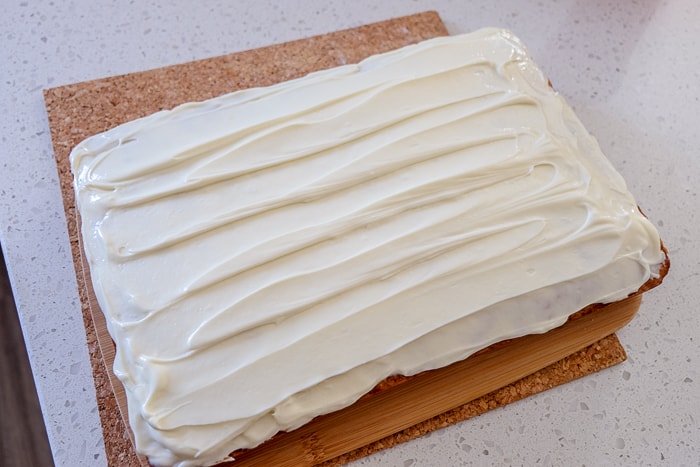 carrot cake with cream cheese icing on top on white counter