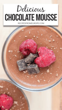 top down view of chocolate mousse in glass with raspberries and chocolate chips on top and text overlay at top saying "delicious chocolate mousse"
