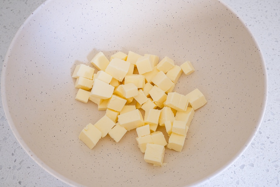 cubes of butter cut in white mixing bowl on counter