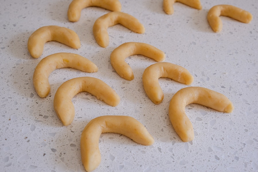 raw crescent cookies in a row on white counter top