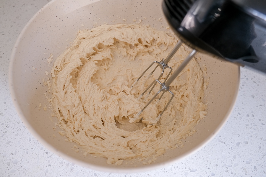 metal beaters mixing cookie dough in white mixing bowl on counter