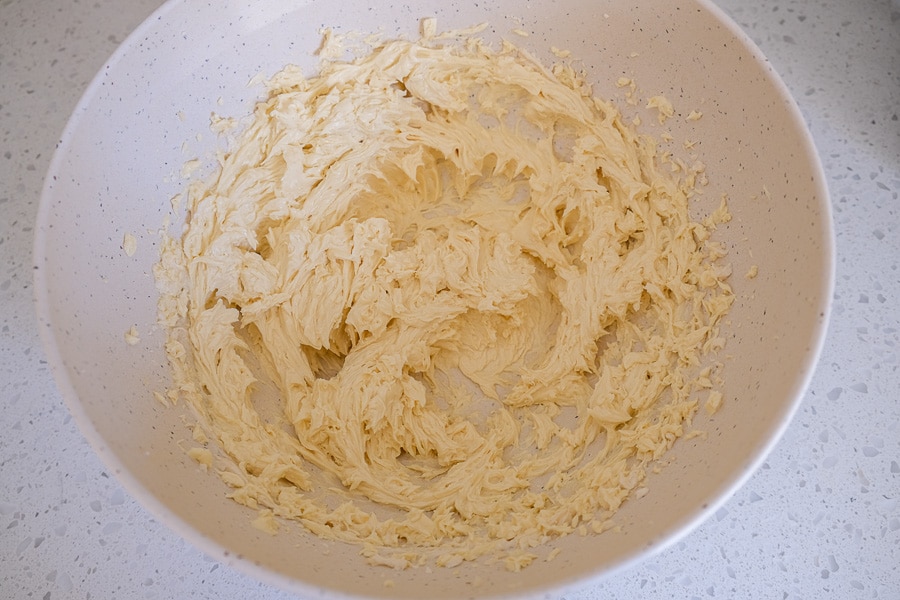 mixed spritz cookie dough in white mixing bowl on counter