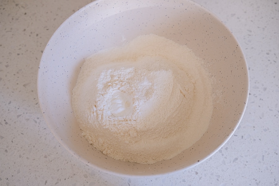 dry ingredients like flour in white mixing bowl on counter top