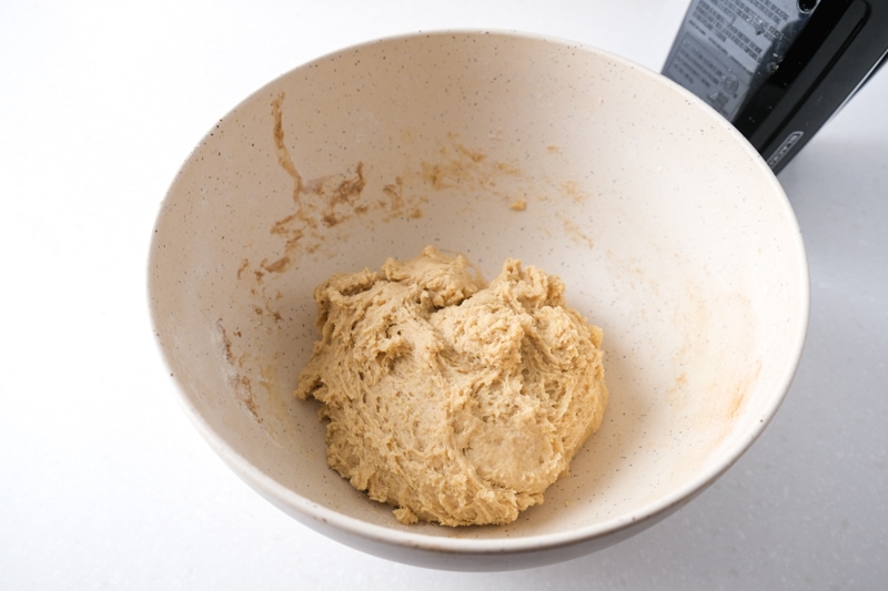 ball of stollen dough sitting in white mixing bowl on white counter.