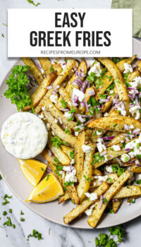 Greek fries with feta, onion, parsley, and lemon on plate plus text overlay "Easy Greek Fries".