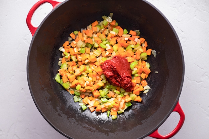 chopped vegetables with tomato paste in black sauce pan on counter.