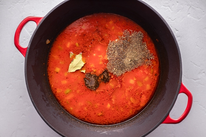 red soup with spices on top in black pot on counter.