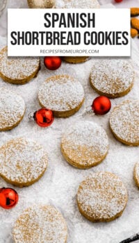 shortbread cookies with powdered sugar on top and small red ornaments next to them plus text overlay "Spanish Shortbread Cookies".