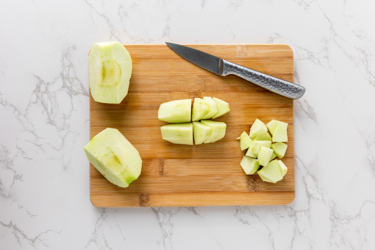 pieces of green apples cut into smaller chunks on wooden cutting board.