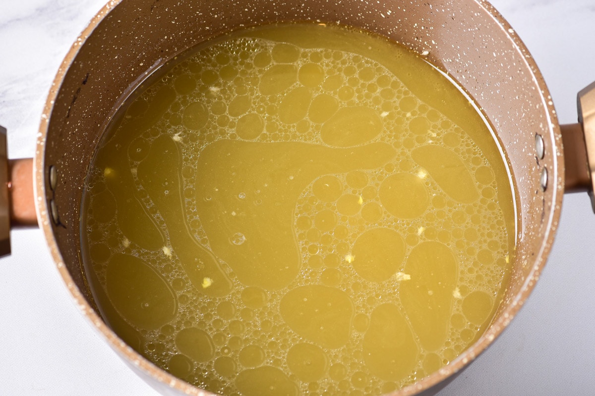 yellow chicken broth in pot with counter top around.