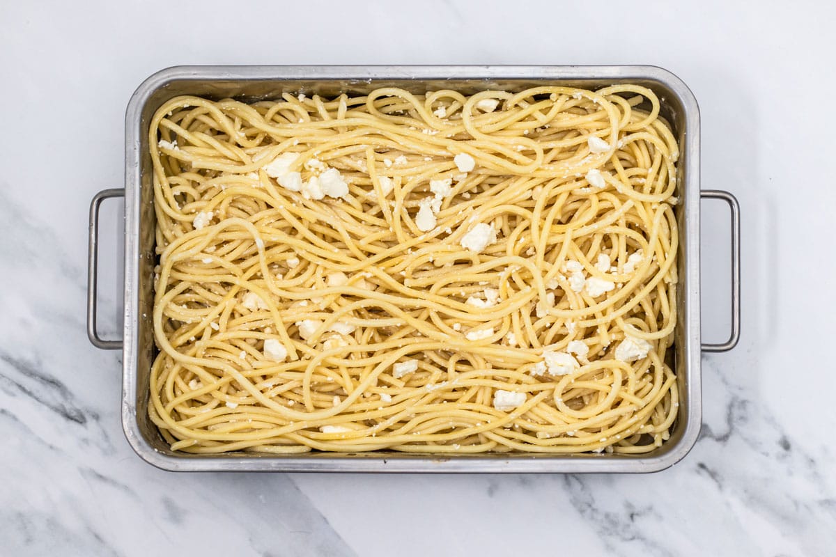 cooked long pasta arranged in rectangle baking dish on counter top.