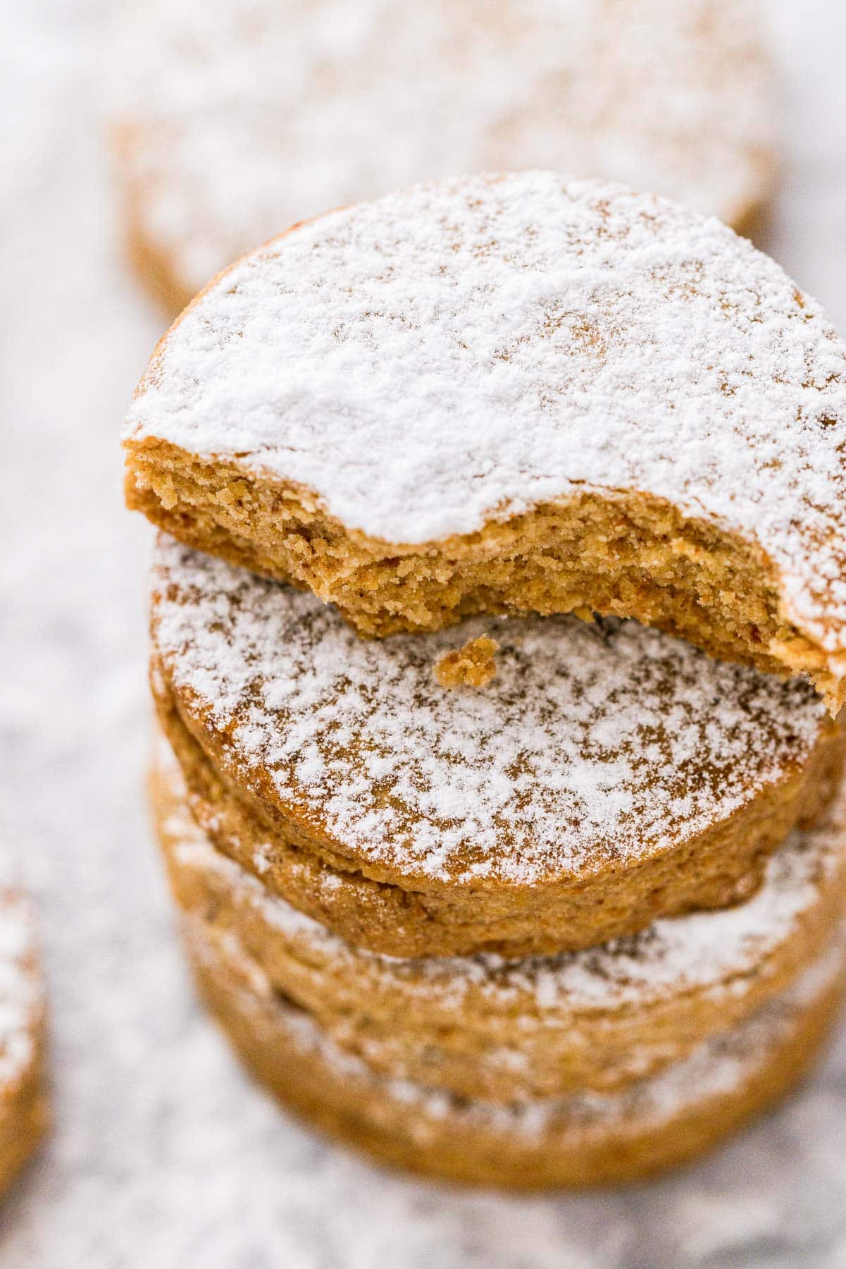 stack of polvorones cookies with bite out of one with cookies behind.