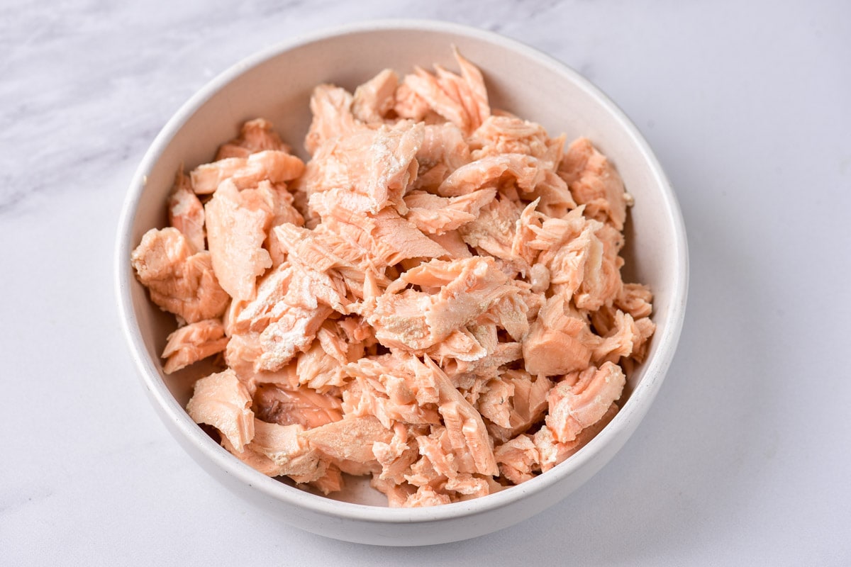 cooked salmon meat in white bowl on counter top.