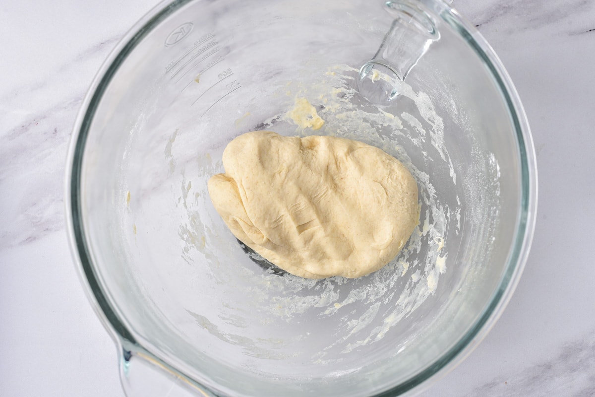 ball of dough in glass mixing bowl on counter.