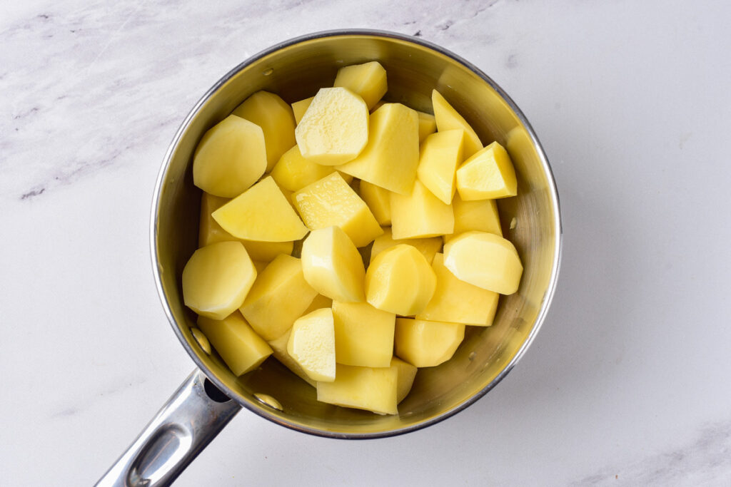 cut potatoes in pot sitting on counter top.