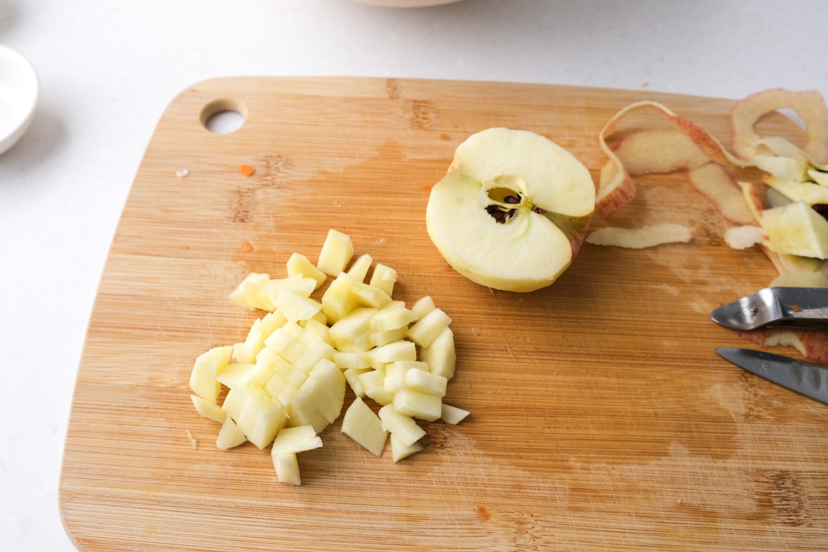 diced apple pieces on wooden cutting board with half an apple beside.