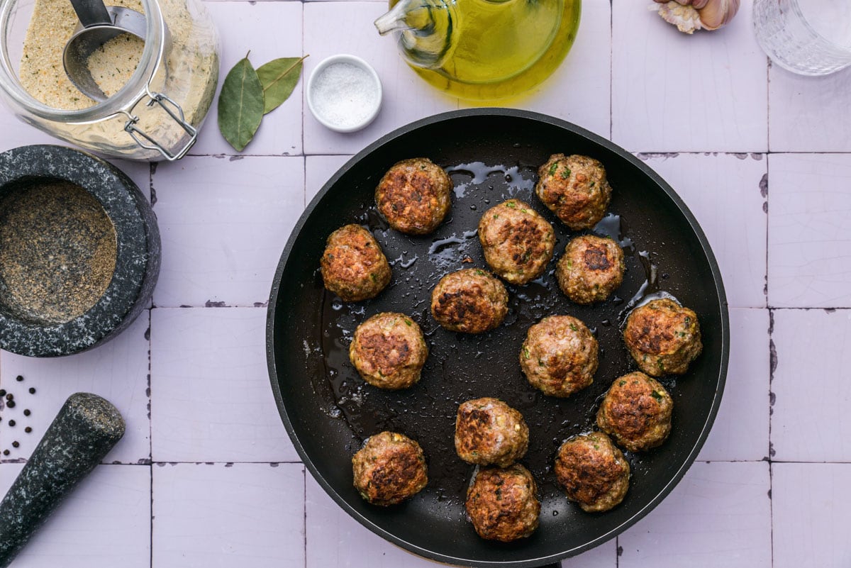 fried meatballs sitting in black cast iron pan on counter top.
