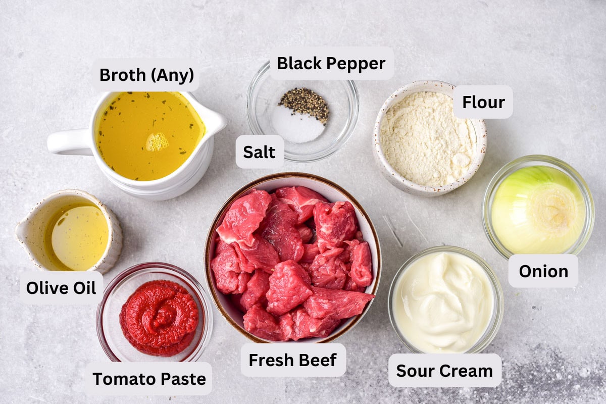 ingredients for beef stroganoff like fresh beef and spices in bowls with labels.