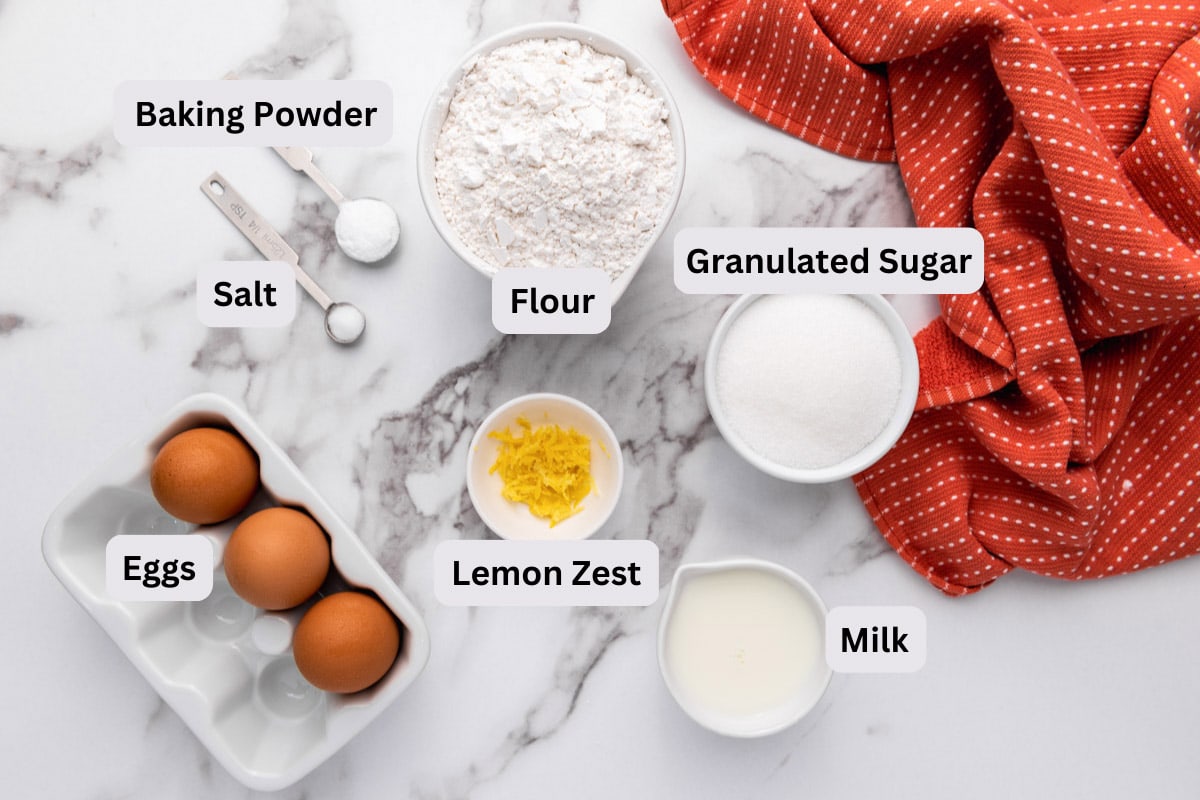 ingredients to make dutch egg cakes on marble counter with labels and red cloth beside.