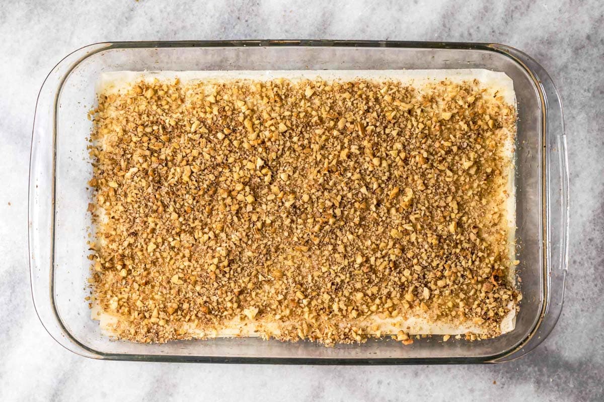 layer of ground nuts sitting on top of phyllo dough in glass baking pan.
