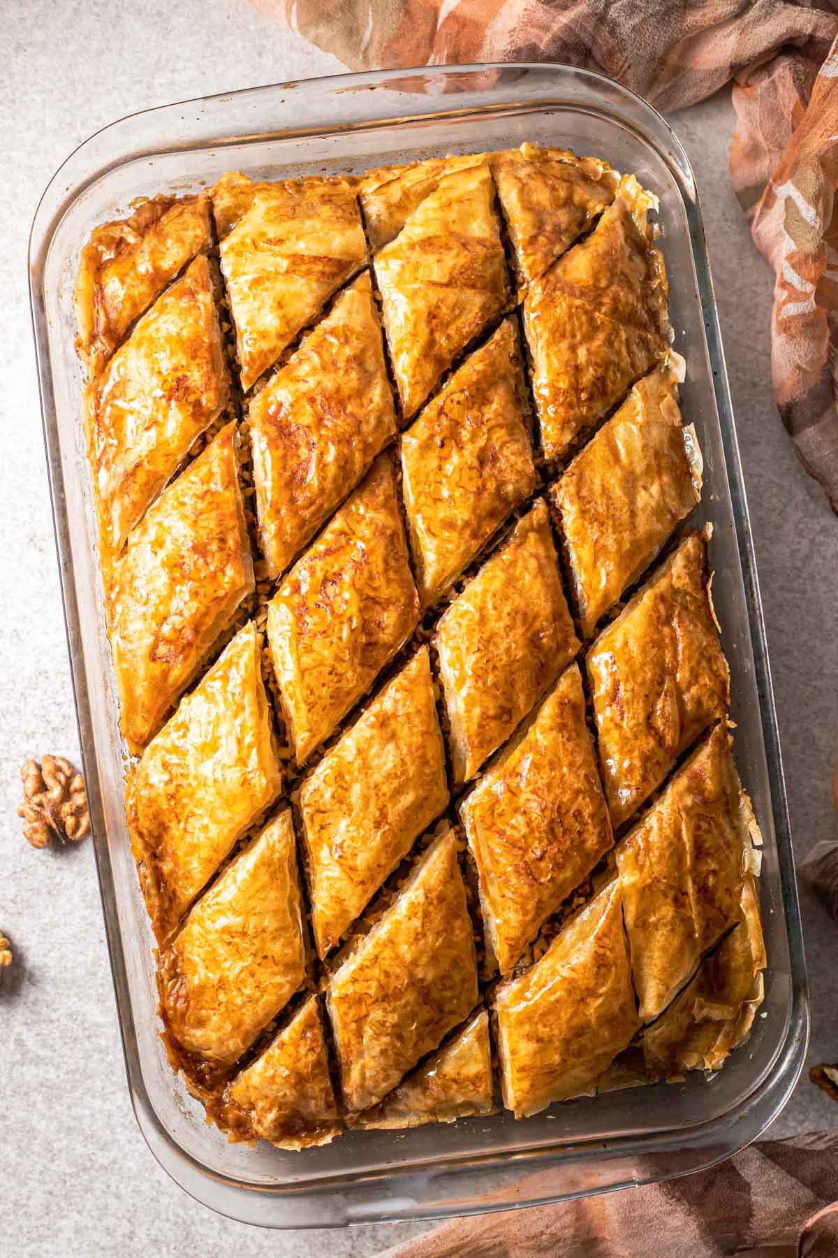 glass pan of greek baklava cut into perfect diamond pieces seen from above.