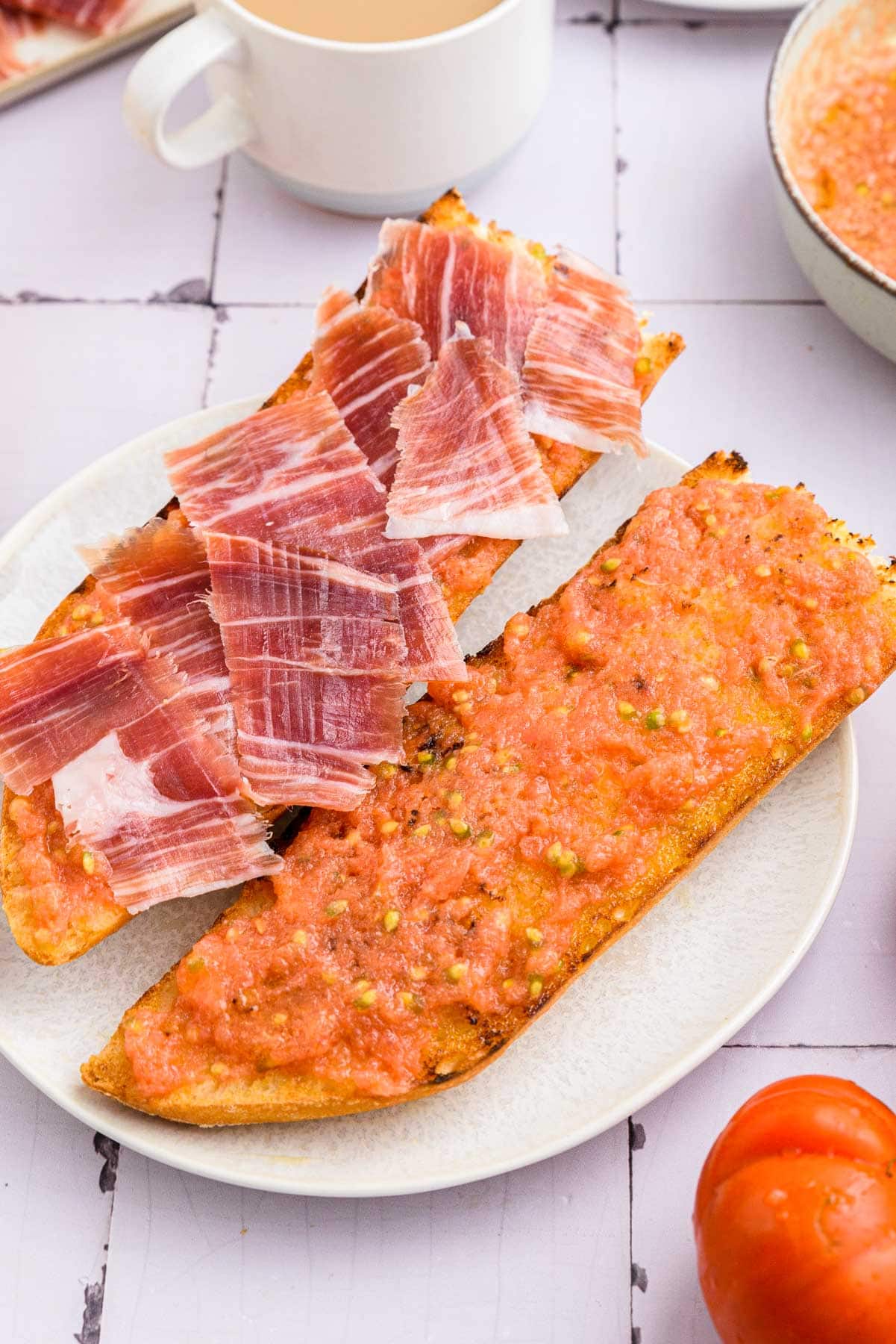 tomato spread on fresh bread with ham placed on top all on white plate.