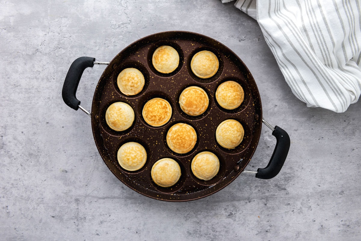 cooked mini dutch pancakes in black cast iron pan on grey counter.