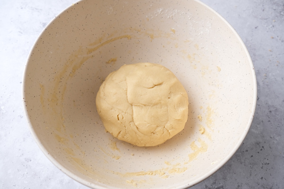 ball of dough sitting in bottom of white mixing bowl.