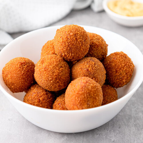 small white bowl of deep fried bitterballen on grey counter.