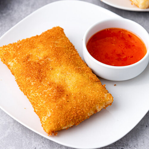 deep fried kaassouffle cheese snack on white plate with red dipping sauce beside.