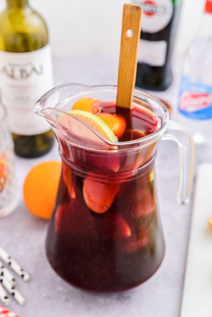 large pitcher of red sangria with wooden spoon sticking out.