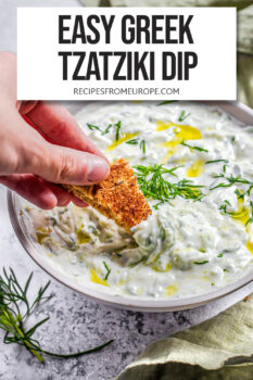hand dipping cracker in tzatziki sauce in bowl with text overlay "easy Greek tzatziki dip".