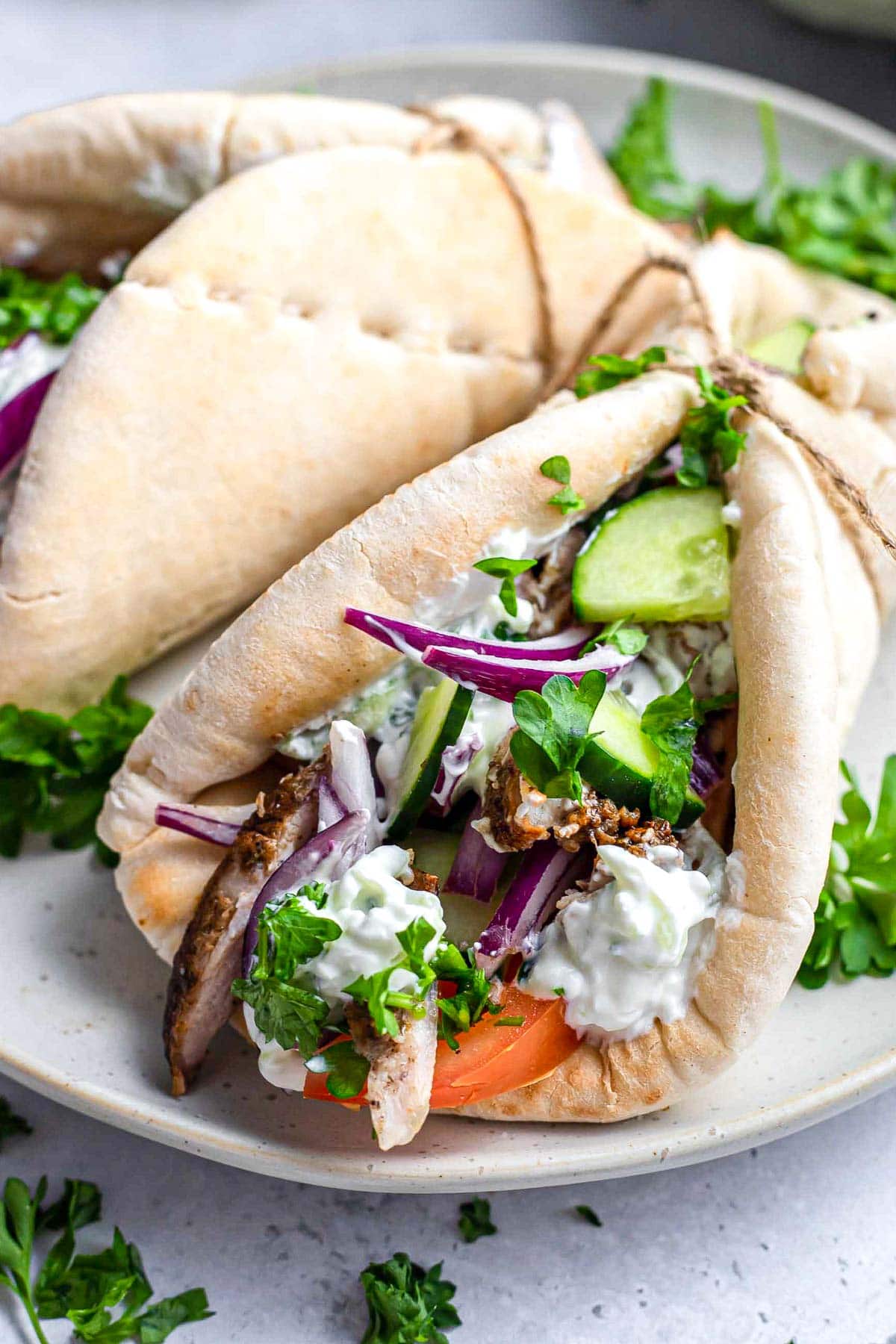 chicken and vegetables wrapped in a pita sitting on a plate.
