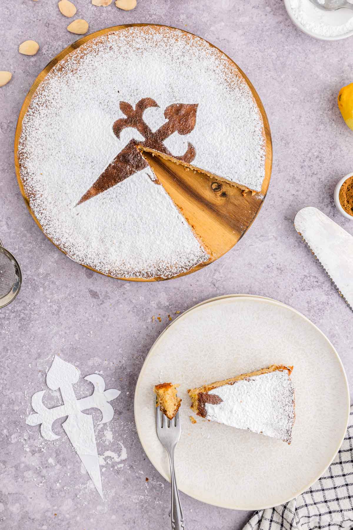 large spanish almond cake with piece removed and on plate with fork.