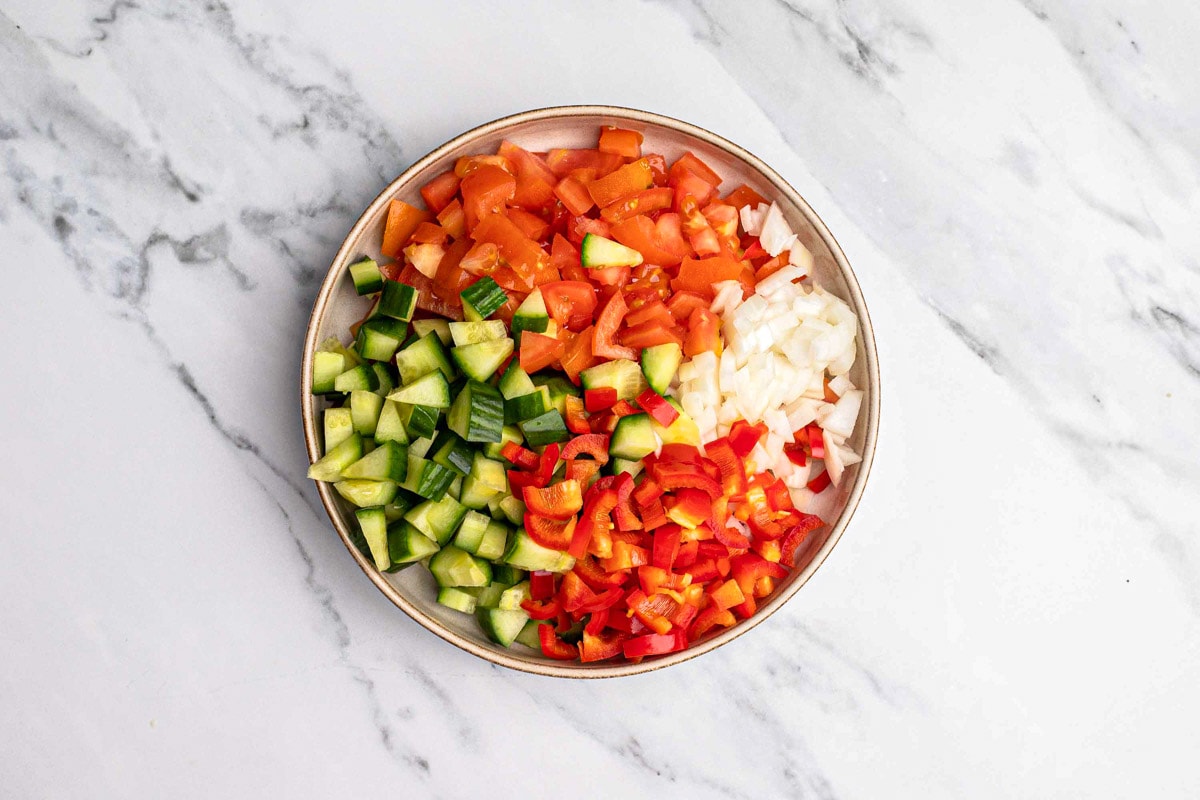 chopped vegetables in large plate on marble counter.