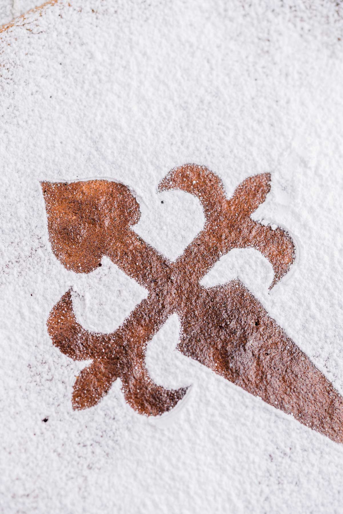 santiago cross shape on top of cake covered in powdered sugar.