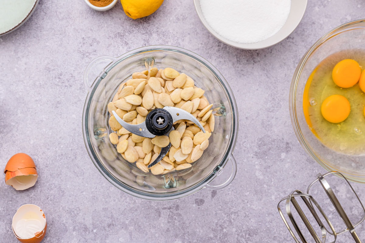 whole almonds in food processor on counter with other ingredients around.