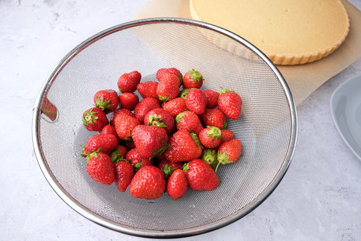 fresh strawberries rinsed in silver colander on counter.