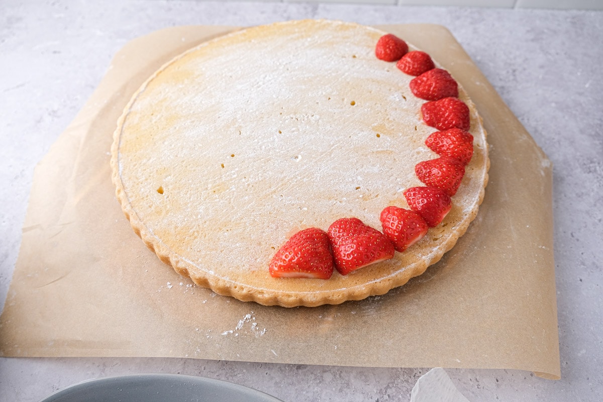 halved strawberries placed in a ring on flat cake bottom.