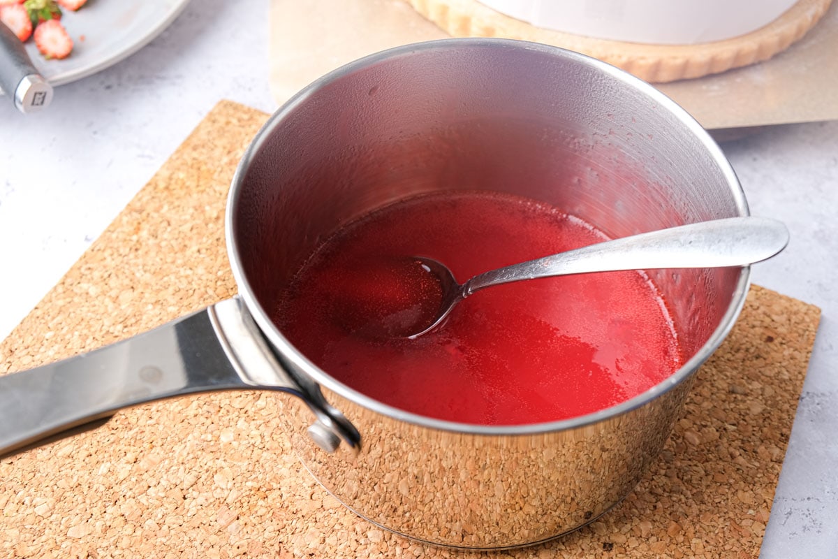 red glaze prepared in silver pot with silver spoon sticking out.