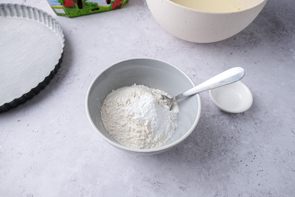 dry ingredients with silver spoon in grey bowl on counter.