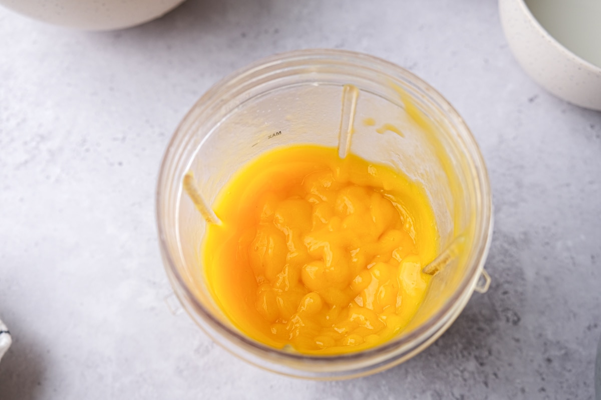 blended mango coulis in plastic tumbler on counter top.