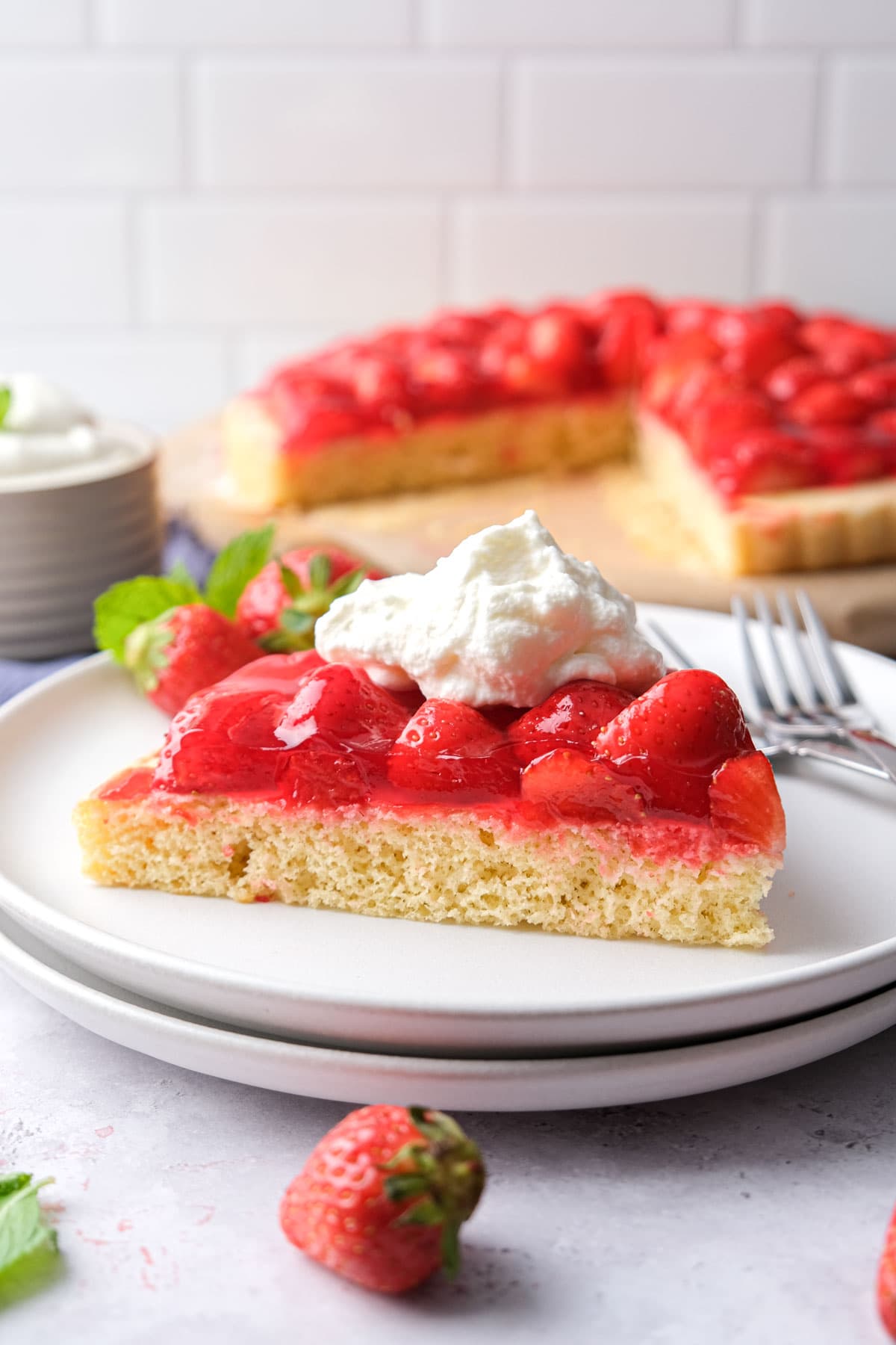 slice of german strawberry cake with dollop of whipping cream on top.