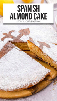 Flat Spanish almond cake with powdered sugar on top and text overlay "Spanish almond cake".